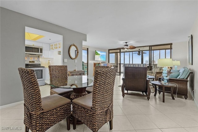 dining room with light tile patterned floors, a ceiling fan, baseboards, and expansive windows