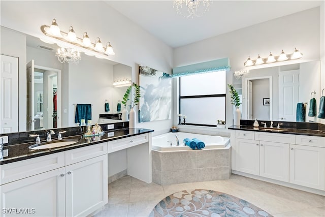 bathroom with tile patterned flooring, vanity, tiled bath, and a notable chandelier