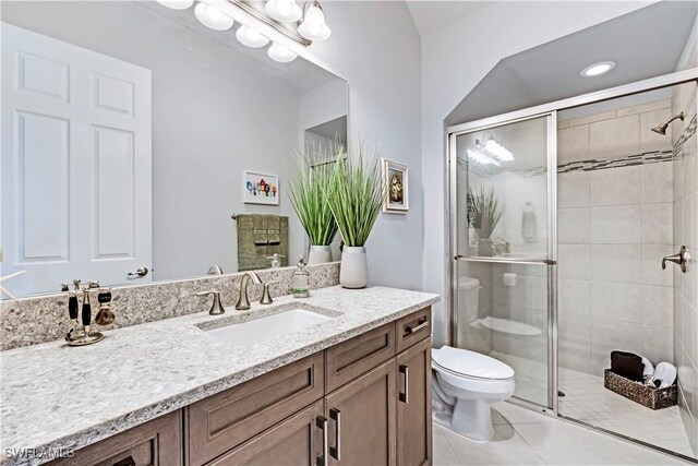 bathroom featuring tile patterned floors, vanity, toilet, and a shower with shower door