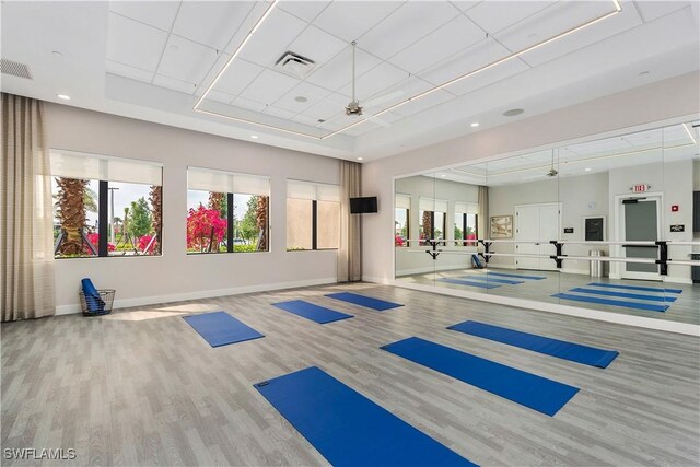 gym with a tray ceiling, basketball hoop, hardwood / wood-style floors, and ceiling fan