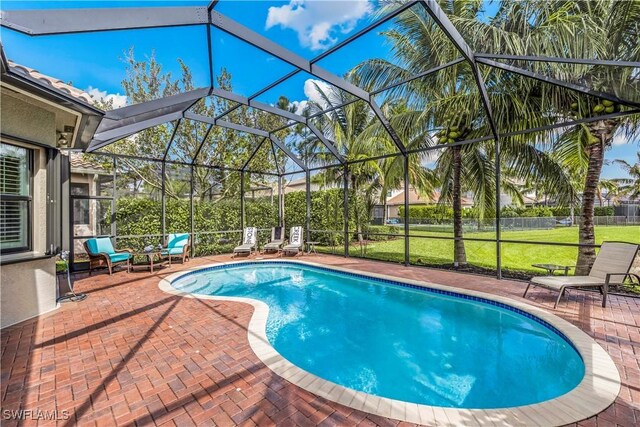 view of swimming pool with glass enclosure, a patio area, and a yard