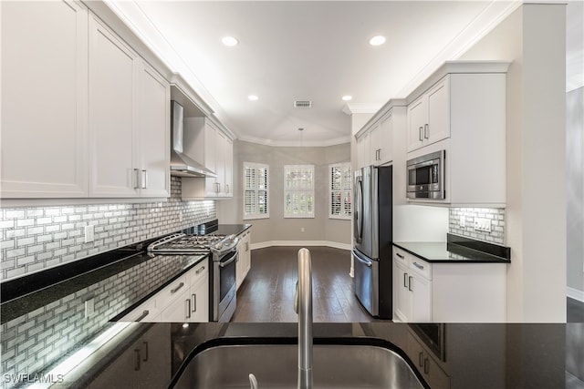 kitchen featuring dark hardwood / wood-style flooring, wall chimney exhaust hood, stainless steel appliances, crown molding, and white cabinets