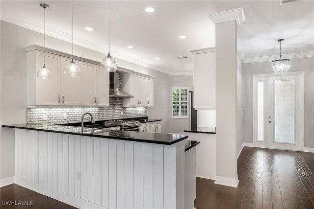 kitchen featuring dark wood-type flooring, stainless steel gas range, kitchen peninsula, decorative light fixtures, and white cabinets