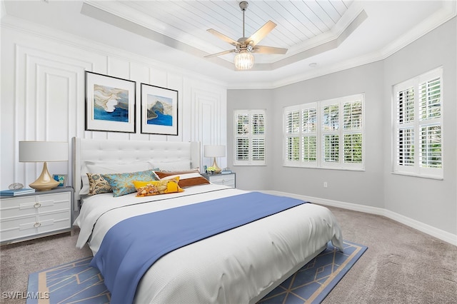 carpeted bedroom with ceiling fan, ornamental molding, and a tray ceiling