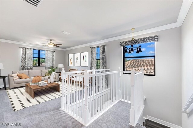 living room featuring carpet floors, ceiling fan with notable chandelier, and ornamental molding