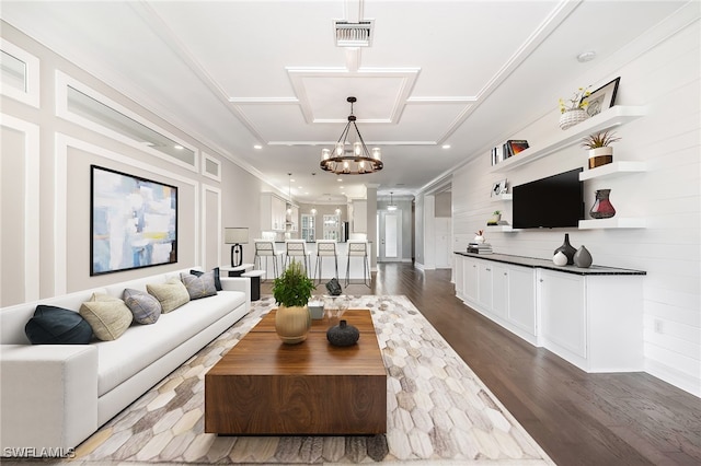 living room featuring hardwood / wood-style flooring, an inviting chandelier, and ornamental molding