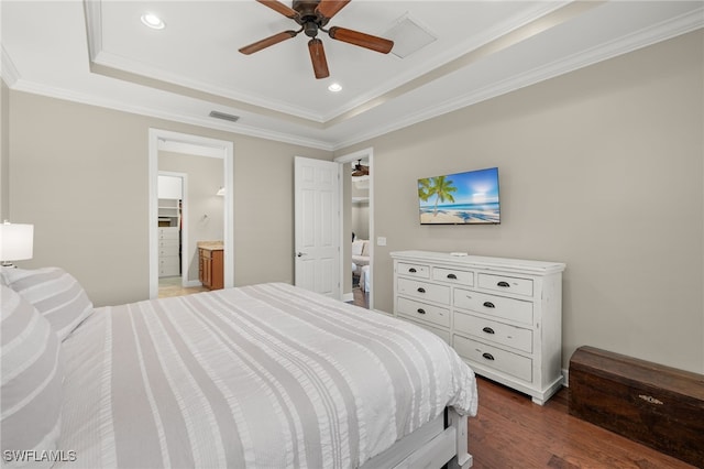 bedroom featuring dark wood-type flooring, a raised ceiling, crown molding, ceiling fan, and connected bathroom