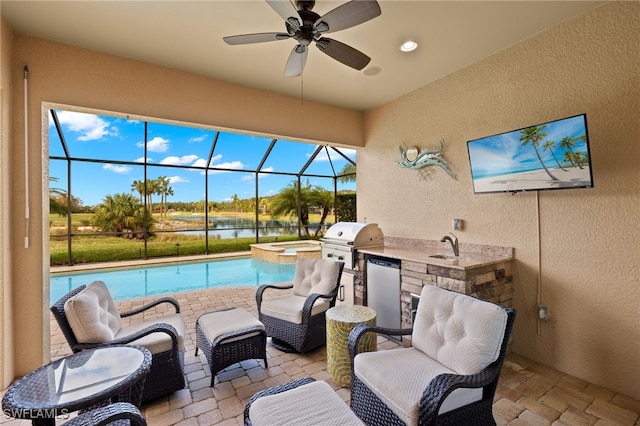 view of pool featuring glass enclosure, area for grilling, a patio area, and an outdoor kitchen