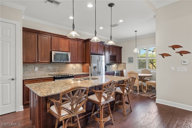 kitchen with pendant lighting, dark hardwood / wood-style floors, an island with sink, and appliances with stainless steel finishes