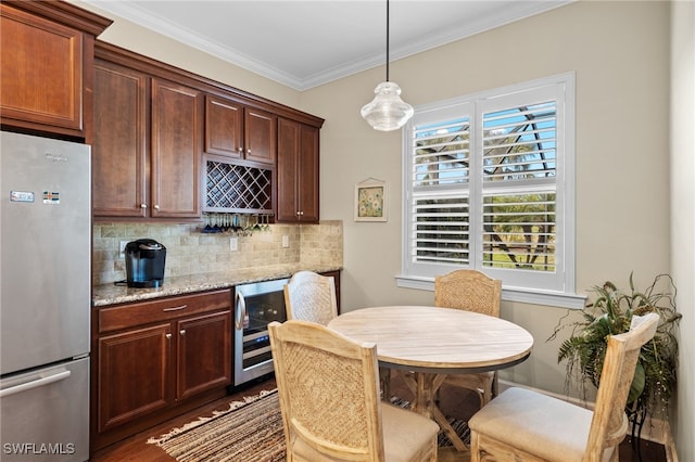 kitchen with stainless steel refrigerator, beverage cooler, light stone counters, pendant lighting, and ornamental molding