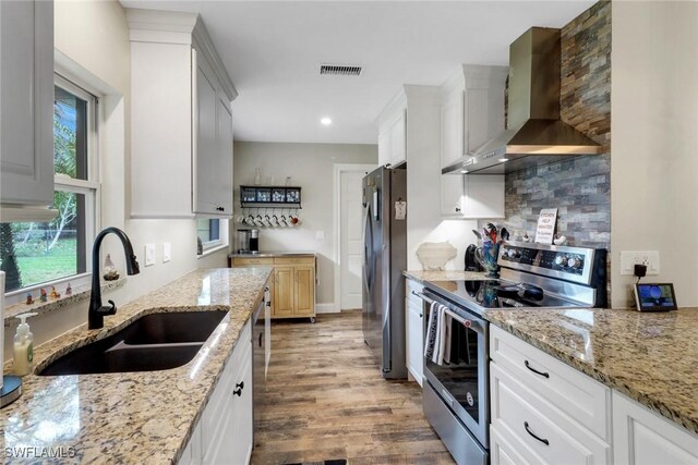 2600 Poinciana St, Naples, FL 34105 - kitchen featuring appliances with stainless steel finishes, wall chimney range hood, a sink, light wood-style floors, and light stone countertops