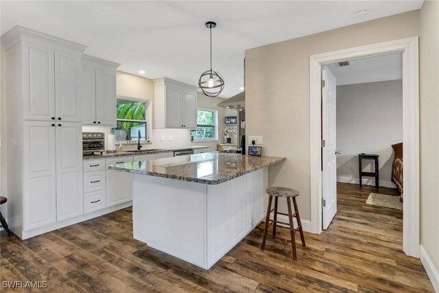 kitchen with dark stone counters, sink, kitchen peninsula, dark hardwood / wood-style flooring, and white cabinetry