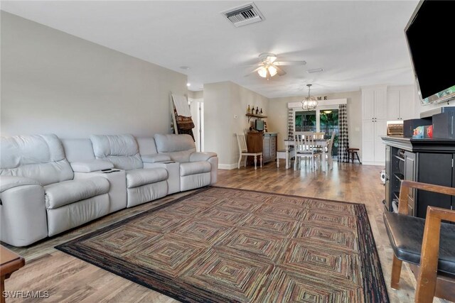 living room with ceiling fan with notable chandelier and wood-type flooring