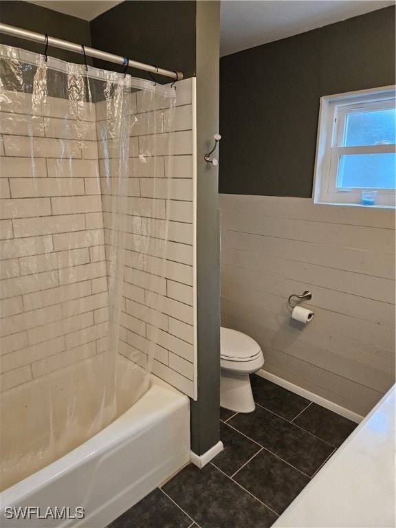 bathroom featuring tile patterned floors, shower / bath combo with shower curtain, tile walls, and toilet