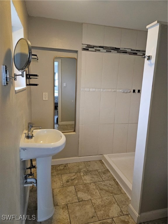 bathroom with tiled shower and sink