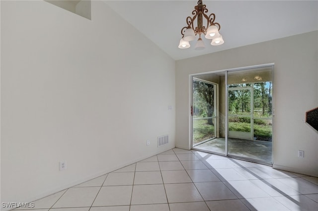 tiled empty room featuring lofted ceiling and a notable chandelier