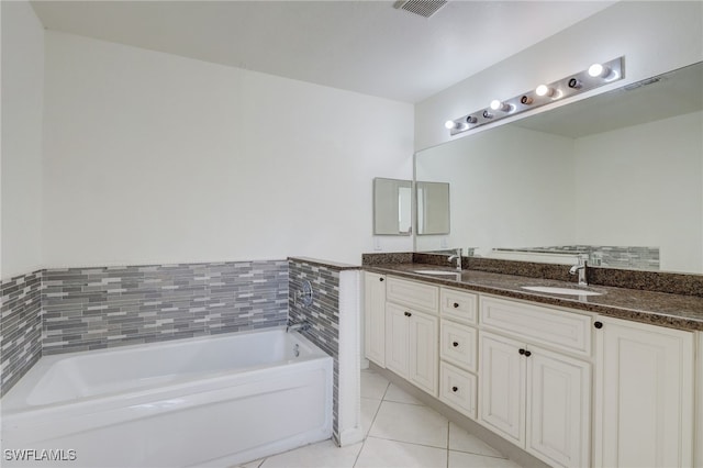 bathroom with a bathing tub, vanity, and tile patterned floors