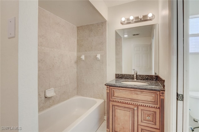 full bathroom featuring tiled shower / bath, vanity, and toilet