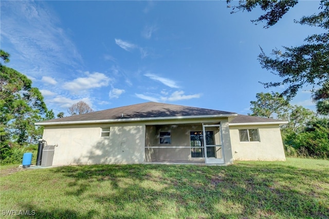 rear view of house featuring a lawn and a sunroom