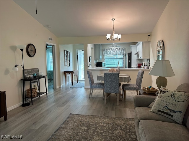 dining room featuring hardwood / wood-style flooring, lofted ceiling, and a chandelier