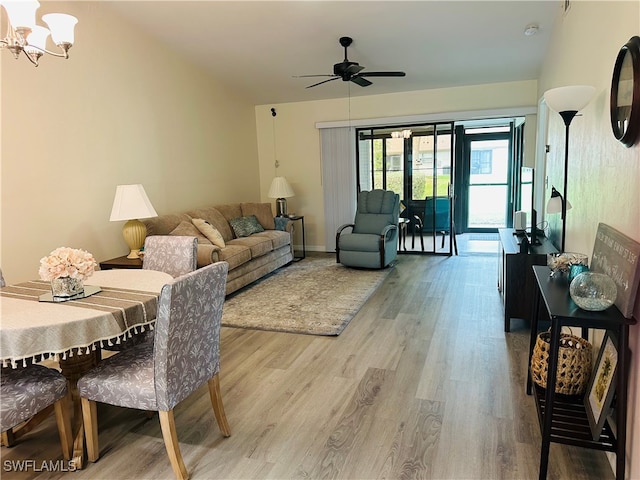 living room featuring ceiling fan with notable chandelier and light hardwood / wood-style floors