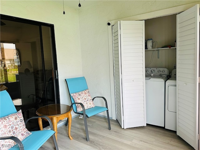 clothes washing area with washer and dryer and light wood-type flooring