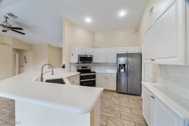 kitchen with sink, backsplash, kitchen peninsula, white cabinets, and appliances with stainless steel finishes