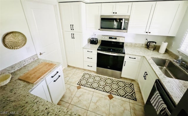 kitchen with light stone countertops, white cabinetry, sink, and stainless steel appliances