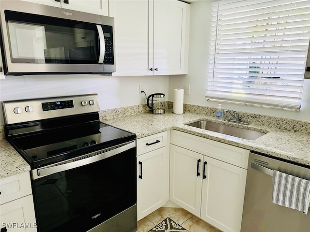 kitchen with light stone countertops, sink, white cabinetry, and stainless steel appliances