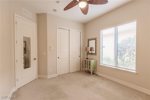 unfurnished bedroom with ceiling fan, light colored carpet, and a closet