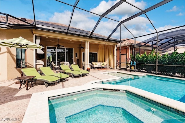 view of swimming pool with a patio area, glass enclosure, an in ground hot tub, ceiling fan, and an outdoor living space