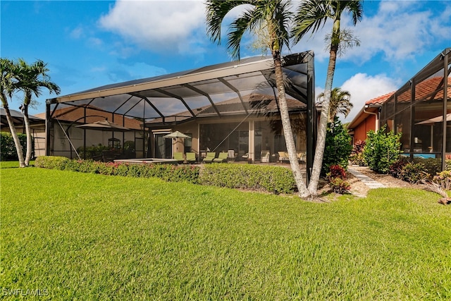 rear view of house with a lanai and a lawn