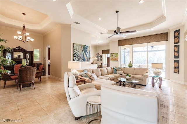 tiled living room featuring crown molding, ceiling fan with notable chandelier, and a tray ceiling