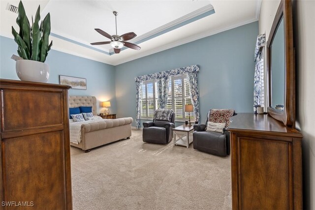 carpeted bedroom with a tray ceiling, ceiling fan, and ornamental molding