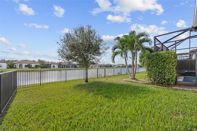 view of yard with glass enclosure, a water view, and a fenced backyard