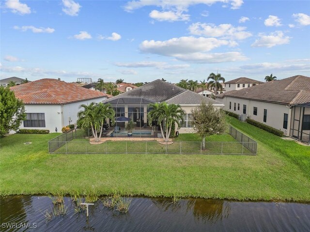 rear view of property featuring a yard, a water view, glass enclosure, and a swimming pool