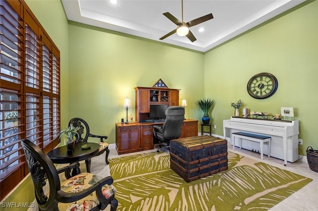 office area with ceiling fan and a tray ceiling