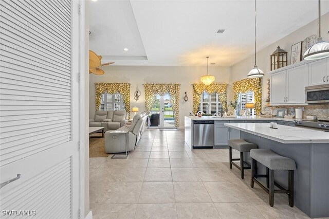 kitchen featuring hanging light fixtures, stainless steel appliances, a kitchen breakfast bar, tasteful backsplash, and light tile patterned flooring