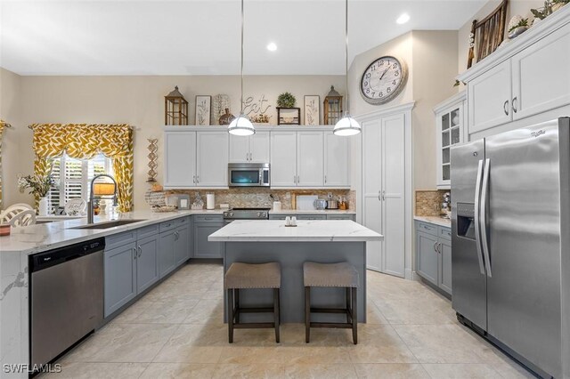 kitchen featuring white cabinetry, sink, stainless steel appliances, pendant lighting, and decorative backsplash