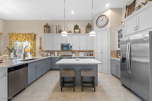 kitchen featuring appliances with stainless steel finishes, a sink, decorative light fixtures, and white cabinets