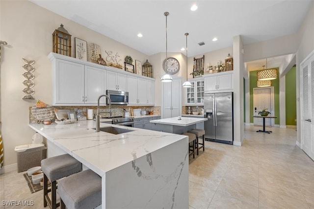 kitchen with a peninsula, a breakfast bar, a kitchen island, appliances with stainless steel finishes, and pendant lighting