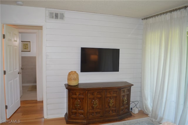 room details featuring a textured ceiling, hardwood / wood-style flooring, and wood walls