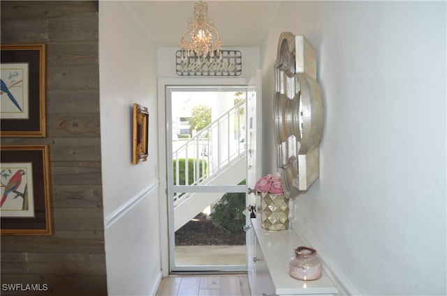 doorway featuring hardwood / wood-style floors, a notable chandelier, and wood walls