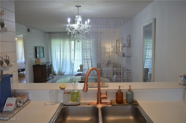 interior space with a textured ceiling, sink, hanging light fixtures, and an inviting chandelier