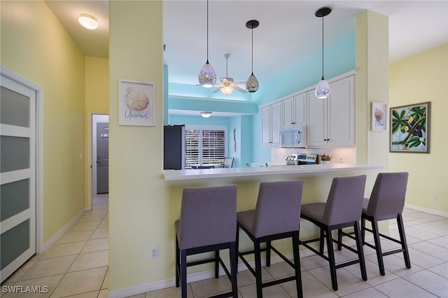 kitchen with pendant lighting, a breakfast bar, white cabinets, and kitchen peninsula