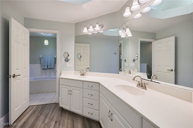 bathroom featuring vanity, wood-type flooring, and a relaxing tiled tub