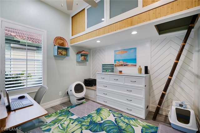 office space featuring wooden walls, ceiling fan, and wood-type flooring