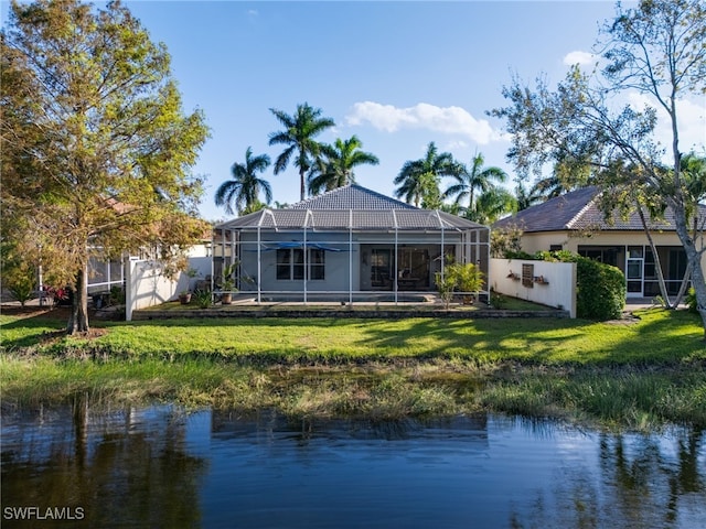 back of property featuring glass enclosure, a water view, and a yard