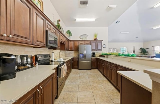 kitchen featuring light tile patterned flooring, appliances with stainless steel finishes, backsplash, and sink