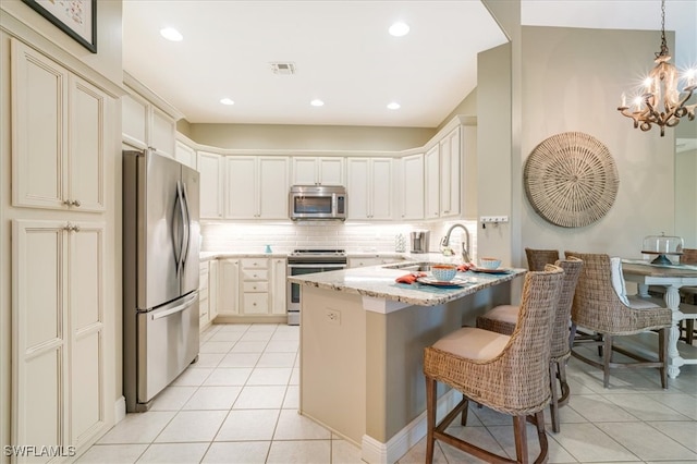 kitchen with light stone countertops, sink, stainless steel appliances, a kitchen breakfast bar, and pendant lighting